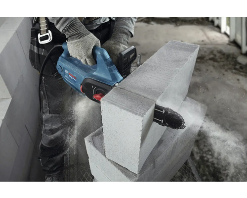 Osoba reže pórobetónovú tvárnicu pílou na kameň.