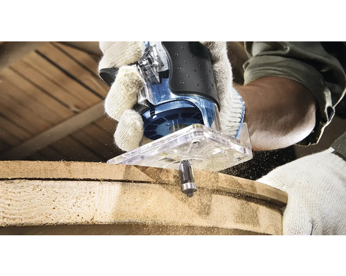 Horná fréza v akcii pri obrábaní kusu dreva. Operátor má na sebe pracovné rukavice.