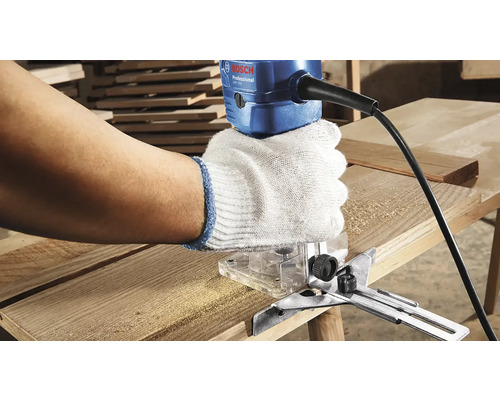 Osoba používa hornú frézku na drevenej doske. Logo Bosch.