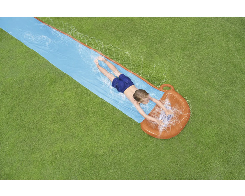 Pohľad zhora na dieťa ležiace na vodnej šmýkačke v záhrade