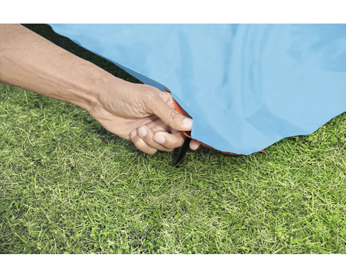 Detailný záber ruky upevňujúcej stan na trávniku.