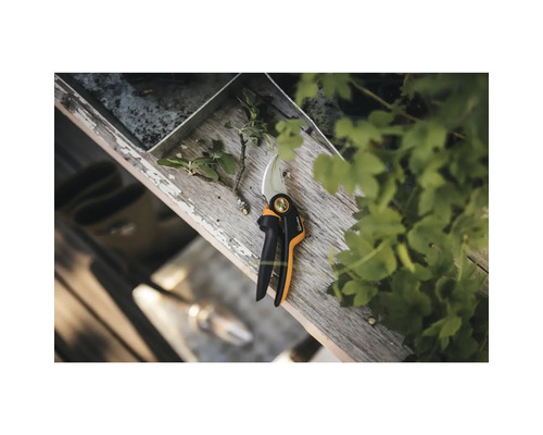 Záhradné nožnice na drevenom povrchu s odrezanou vetvou