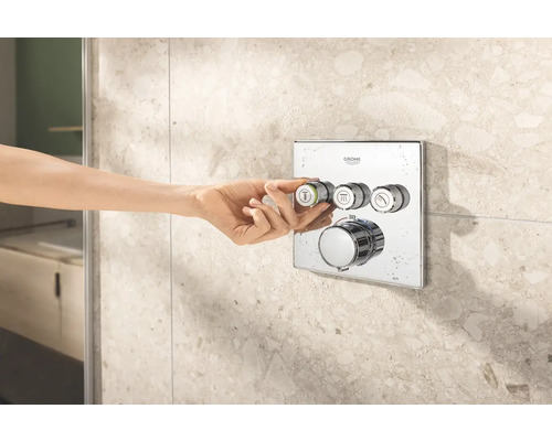 Logo Grohe. Nástenná termostatická batéria s ručným ovládaním pred obkladanou stenou.