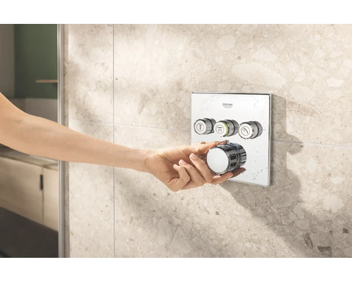 Ruka ovláda sprchovú armatúru Grohe na obloženej stene