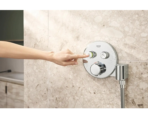 Ruka ovláda sprchovú batériu Grohe na obkladanej stene.