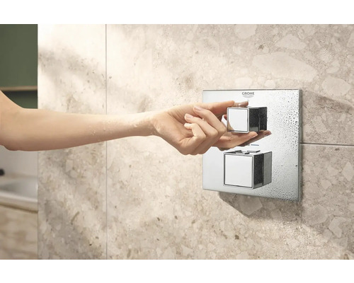 Detailný záber ruky ovládajúcej sprchový termostat Grohe