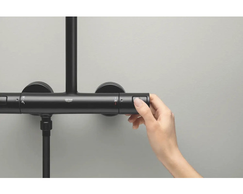 Detail čierneho sprchového kohútika s rukou stlačením tlačidla