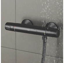 Čierny sprchový termostat Grohe so sprchovou hadicou na obkladanej stene