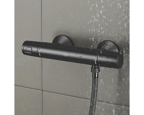Čierny sprchový termostat Grohe so sprchovou hadicou na obkladanej stene