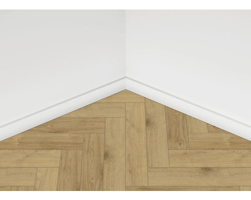 Detail rohu miestnosti s laminátovou podlahou vo vzore rybej kosti a bielou podlahovou lištou na bielej stene