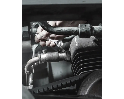 Ruka uťahuje skrutku na motore račňovým kľúčom