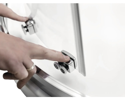 Detailný záber dverí sprchovacieho kúta s valčekovým mechanizmom a rukou, ktorá sa ich dotýka