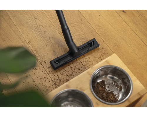 Vysávač čistí podlahu vedľa misky na krmivo