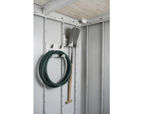 Záhradná hadica a rýľ na nástennom držiaku v kôlni