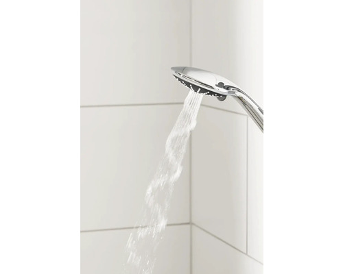 Sprchová hlavica s prúdom vody na pozadí bielych dlaždíc