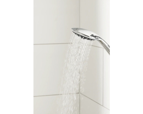 Ručná sprcha s tečúcou vodou pred bielo obloženou stenou