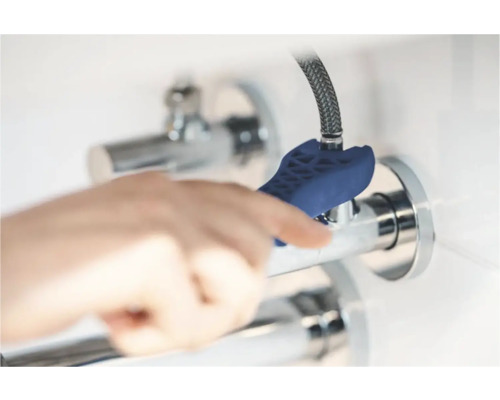 Ruka používa kľúč na vodovodné batérie na montáž vodovodnej batérie.