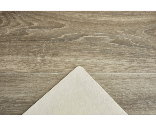 Detailný pohľad na povrch drevenej podlahy so svetlou plstenou podložkou