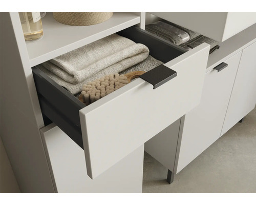 Kúpeľňový nábytok s otvorenou zásuvkou plnou uterákov a kefy.