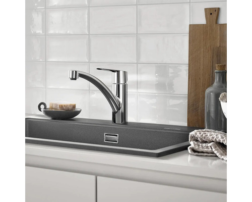 Kuchynská scéna s drezovou batériou, drezom a kuchynskými potrebami.