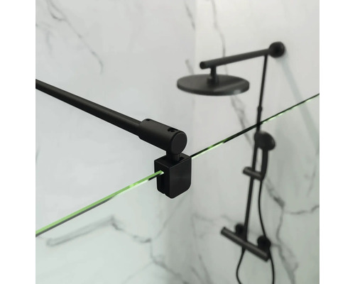 Detailný záber sprchovacieho kúta s čiernym držiakom a sprchovou hlavicou pred mramorovou stenou