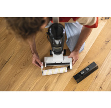 Muž vymieňa čistiacu valec elektrického mopu na drevenej podlahe