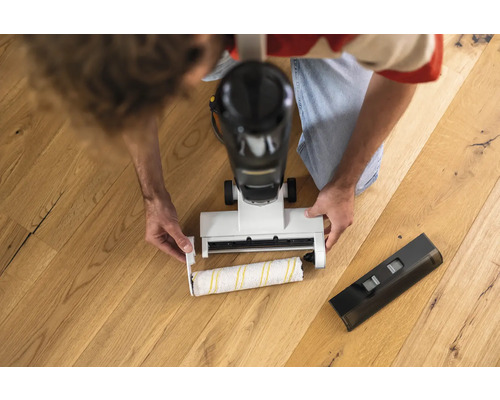 Muž vymieňa čistiacu valec elektrického mopu na drevenej podlahe