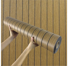 Rola nábytkovej fólie s dreveným dizajnom držaná v rukách