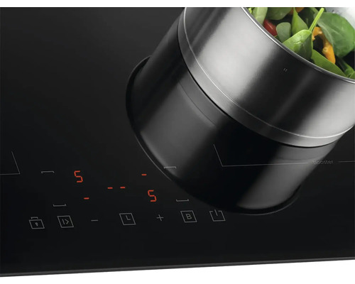 Indukčná varná doska s hrncom a zeleninou.