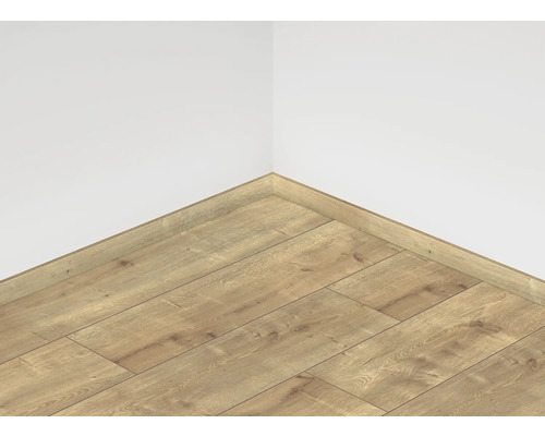 Položená laminátová podlaha s ladiacou soklovou lištou pri stene izby