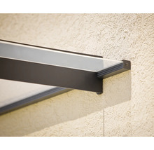 Detail úchytu modernej sklenenej striešky s tmavým kovovým rámom na štruktúrovanej stene.