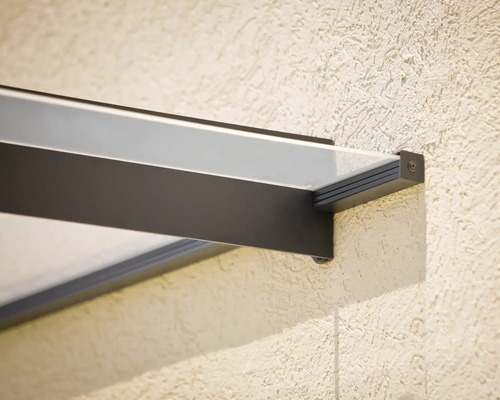 Detail úchytu modernej sklenenej striešky s tmavým kovovým rámom na štruktúrovanej stene.