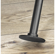 Detailný záber čiernej nohy nábytku s pätkou na drevenej podlahe.