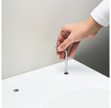 Osoba vkladá imbusový kľúč do otvoru v bielom povrchu