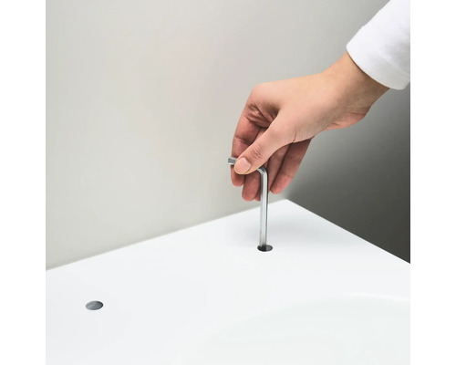 Osoba vkladá imbusový kľúč do otvoru v bielom povrchu