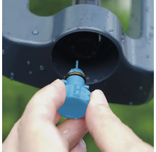 Detailný záber ruky vkladajúcej trysku do zavlažovača trávnika.