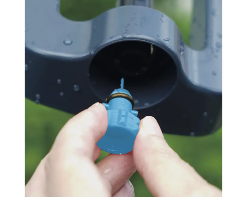 Detailný záber ruky vkladajúcej trysku do zavlažovača trávnika.