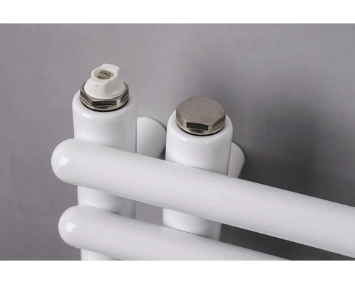 Detailný záber na odvzdušňovací ventil a záslepku na bielom radiátore.