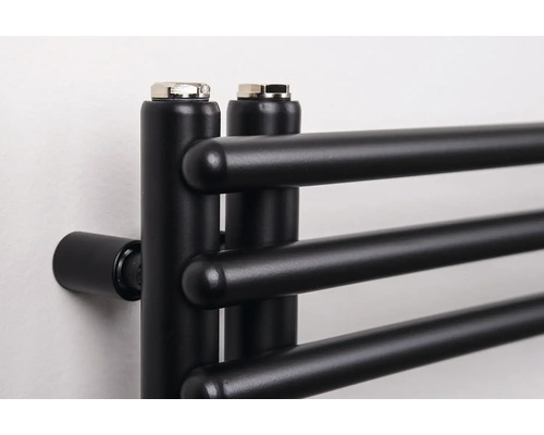 Detailný záber na čierny kúpeľňový radiátor s horizontálnymi okrúhlymi rúrkami a odvzdušňovacími zátkami hore.