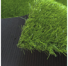 Detailný záber na umelý trávnik s hustými zelenými steblami a tmavou štruktúrovanou spodnou stranou.