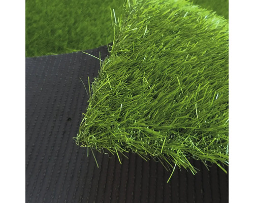 Detailný záber na umelý trávnik s hustými zelenými steblami a tmavou štruktúrovanou spodnou stranou.