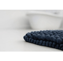 Tmavomodrá kúpeľňová predložka so žinylkovou štruktúrou pred vaňou.