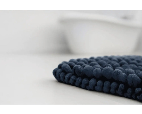 Tmavomodrá kúpeľňová predložka so žinylkovou štruktúrou pred vaňou.