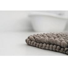 Detailný pohľad na mäkkú kúpeľňovú predložku so žinylkovou štruktúrou pri vani.