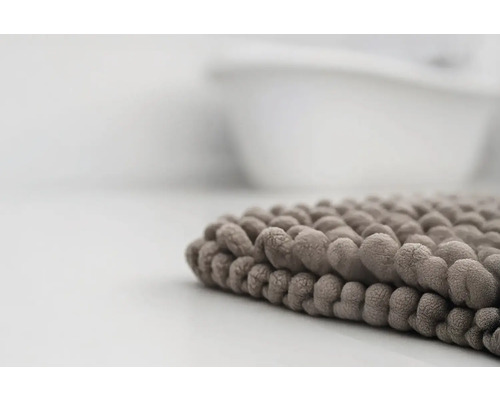 Detailný pohľad na mäkkú kúpeľňovú predložku so žinylkovou štruktúrou pri vani.