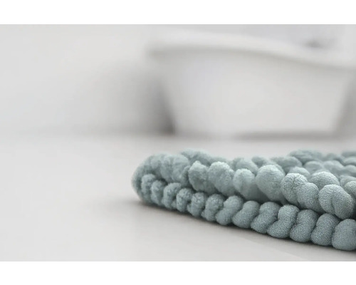 Detailný záber na mäkkú kúpeľňovú predložku z mikrovlákna s žinylkovou štruktúrou v kúpeľni pred vaňou.