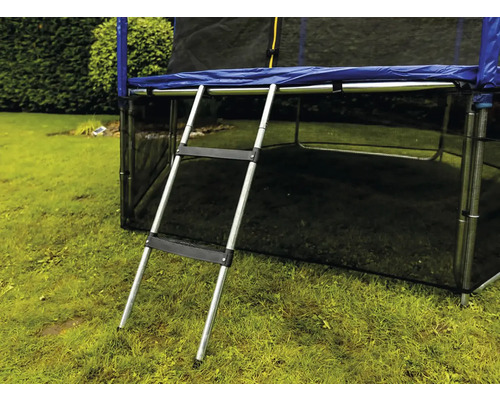 Strieborný kovový rebrík k trampolíne s dvoma čiernymi plastovými stupňami pripevnený k trampolíne na záhrade.