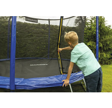 Dieťa otvára žltý zips na ochrannej sieti trampolíny Marimex s modrým krytom pružín v záhrade.