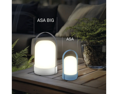 Dve moderné LED lampy ASA BIG a ASA na drevenom stole, atmosférické vonkajšie osvetlenie s rastlinami a pohovkou v pozadí.