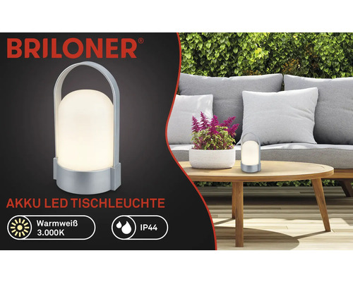 Logo Briloner, stolná LED lampa na akumulátor, teplá biela 3000 kelvinov, IP44, prenosná s rúčkou, na záhrade na drevenom stole.